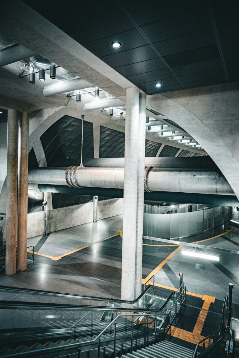 A worker inspects a metal trench drain grate installed in a concrete warehouse floor.