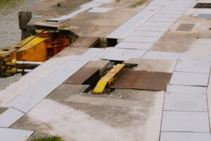 Construction workers installing a trench drain along a new commercial parking lot with visible curbs and concrete paving.
