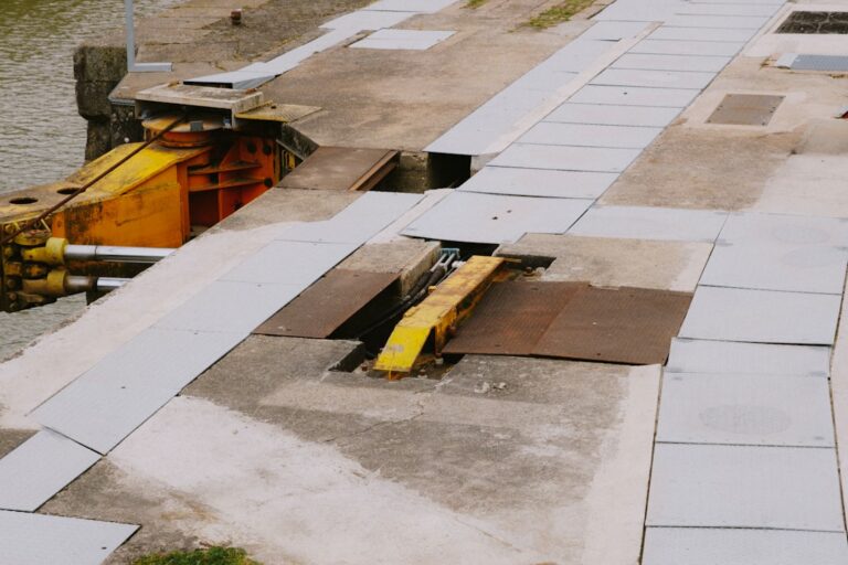 Construction workers installing a trench drain along a new commercial parking lot with visible curbs and concrete paving.
