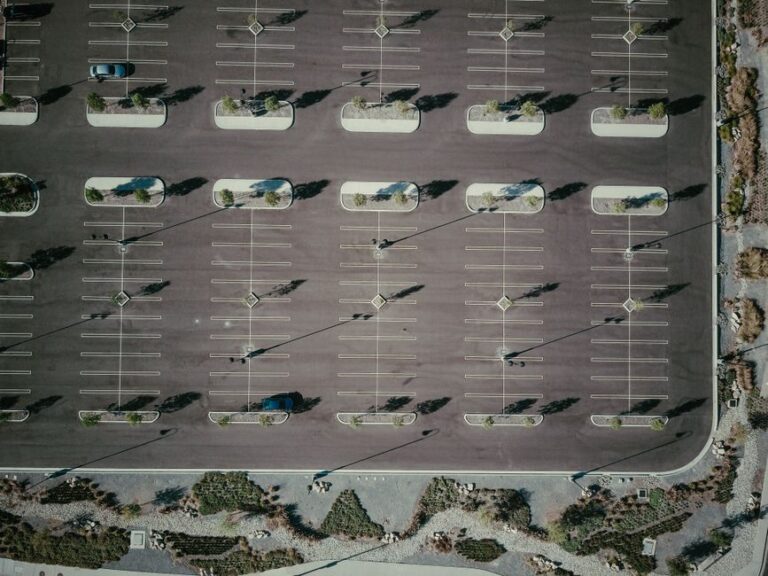 Linear trench drain collecting rainwater across a paved parking lot near a building entrance