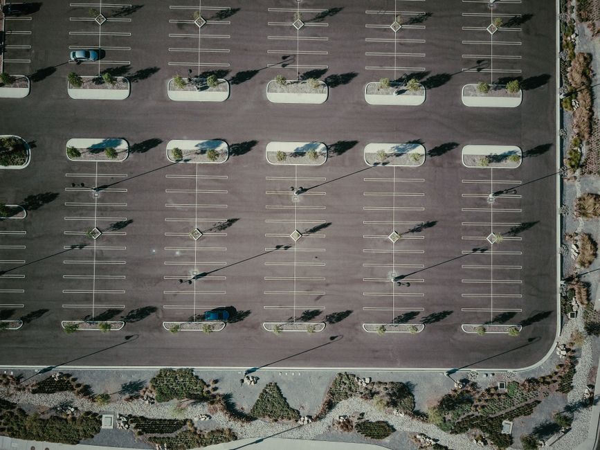 Linear trench drain collecting rainwater across a paved parking lot near a building entrance