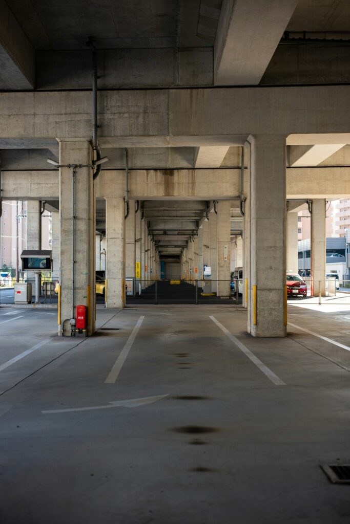 Trench drain crossing a parking garage ramp beside parked vehicles and wet concrete.